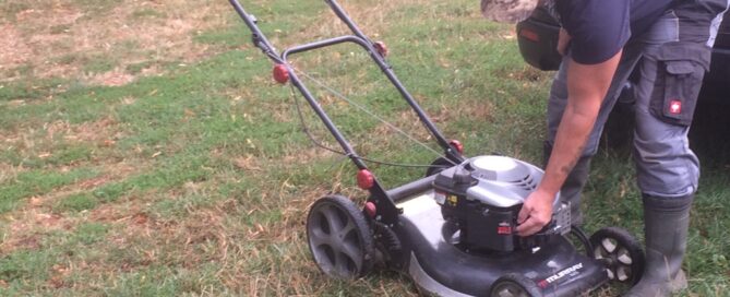 Ein Mitglied des Vereins schraubt an einem Rasenmäher.